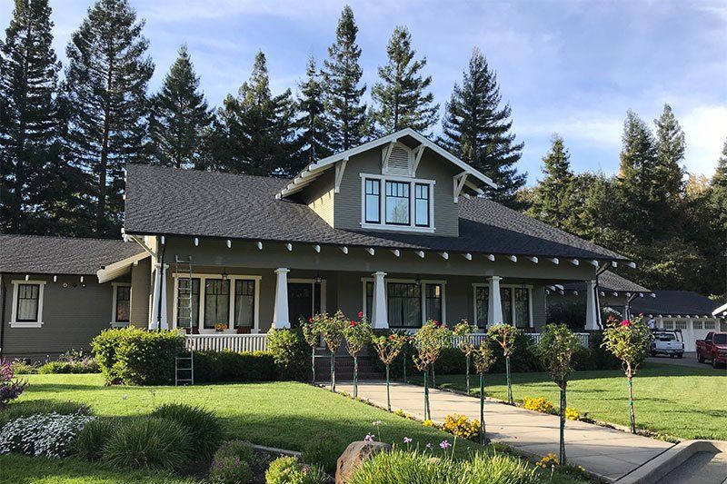 A large house with a black roof is surrounded by trees