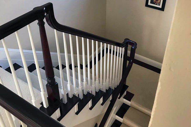 A staircase with a black and white railing and a picture on the wall.
