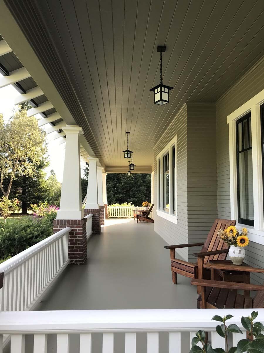 A porch with chairs and a vase of sunflowers