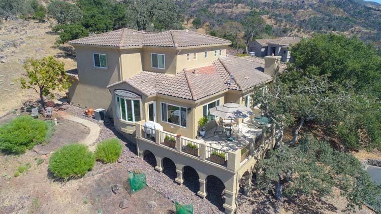 An aerial view of a large house on top of a hill surrounded by trees.