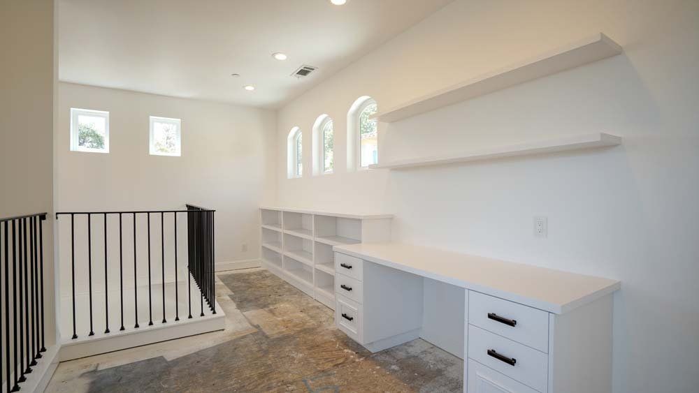 A room with a desk , shelves , and a railing.