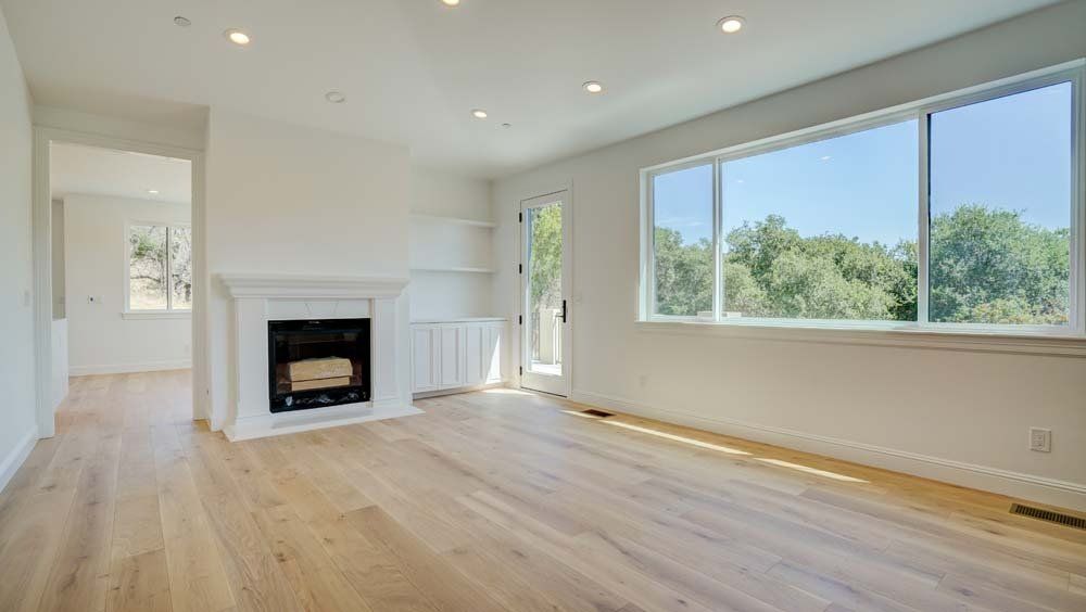 An empty living room with hardwood floors and a fireplace.