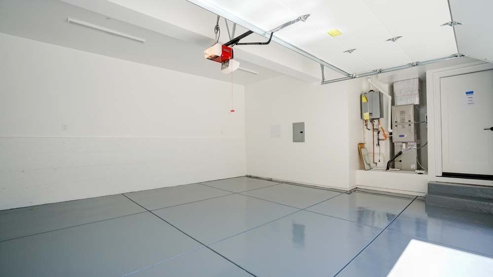 An empty garage with a garage door opener and a gray floor.