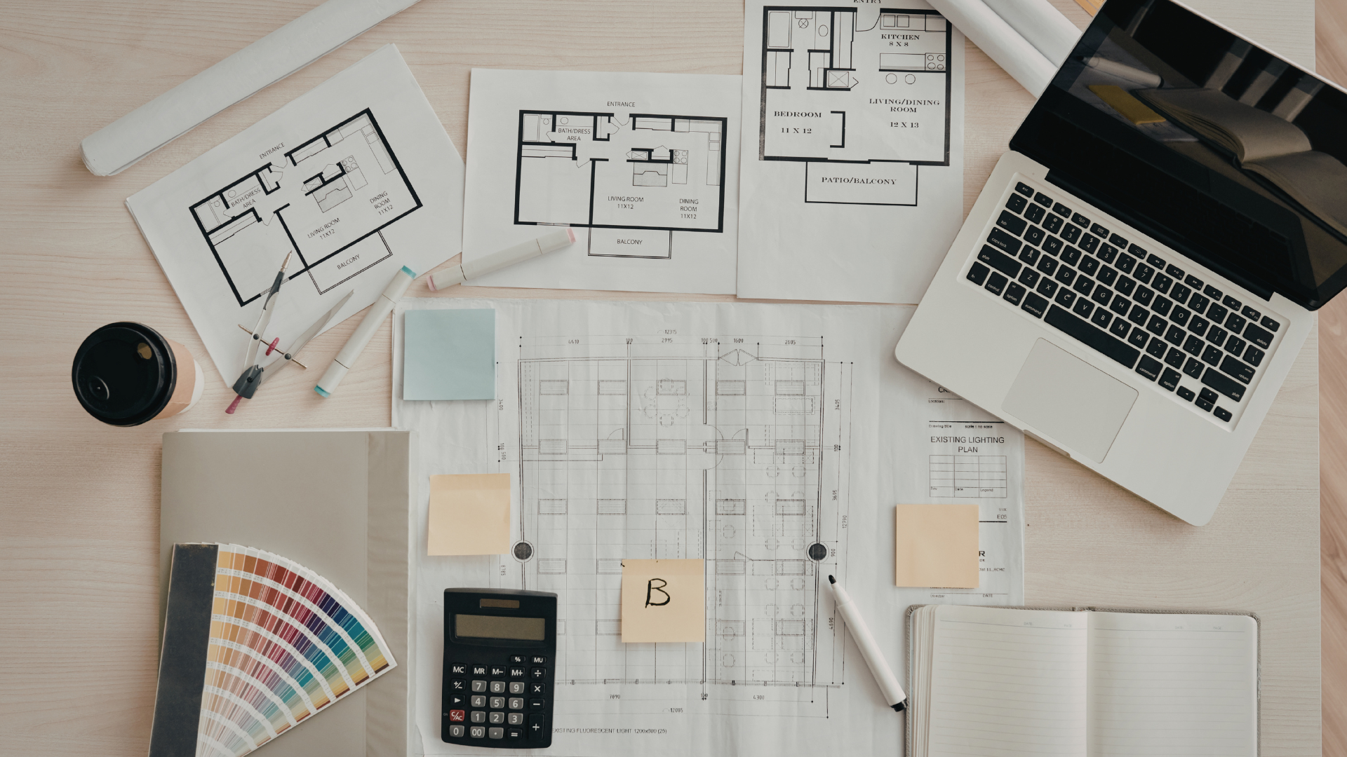 Hands using a pen and ruler to draw on architectural blueprints.