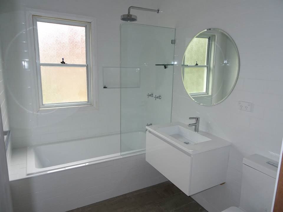 A Bathroom with a Bathtub, Sink, Mirror and Window — Illawarra Bathrooms in Wollongong, NSW