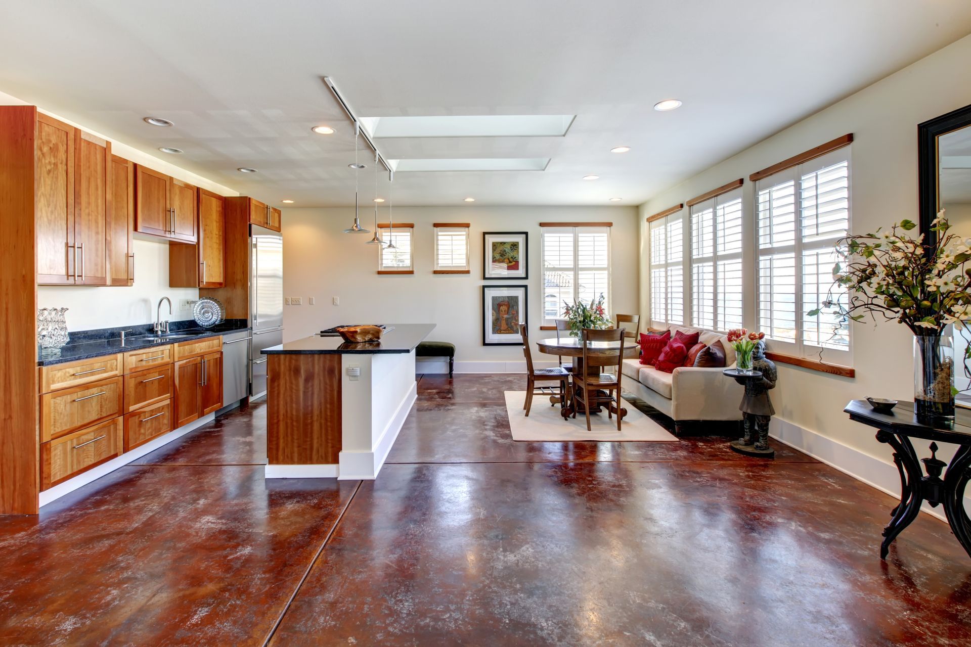 Bright kitchen with wood cabinets, a stainless steel island, and a dining area with a round table and sofa.