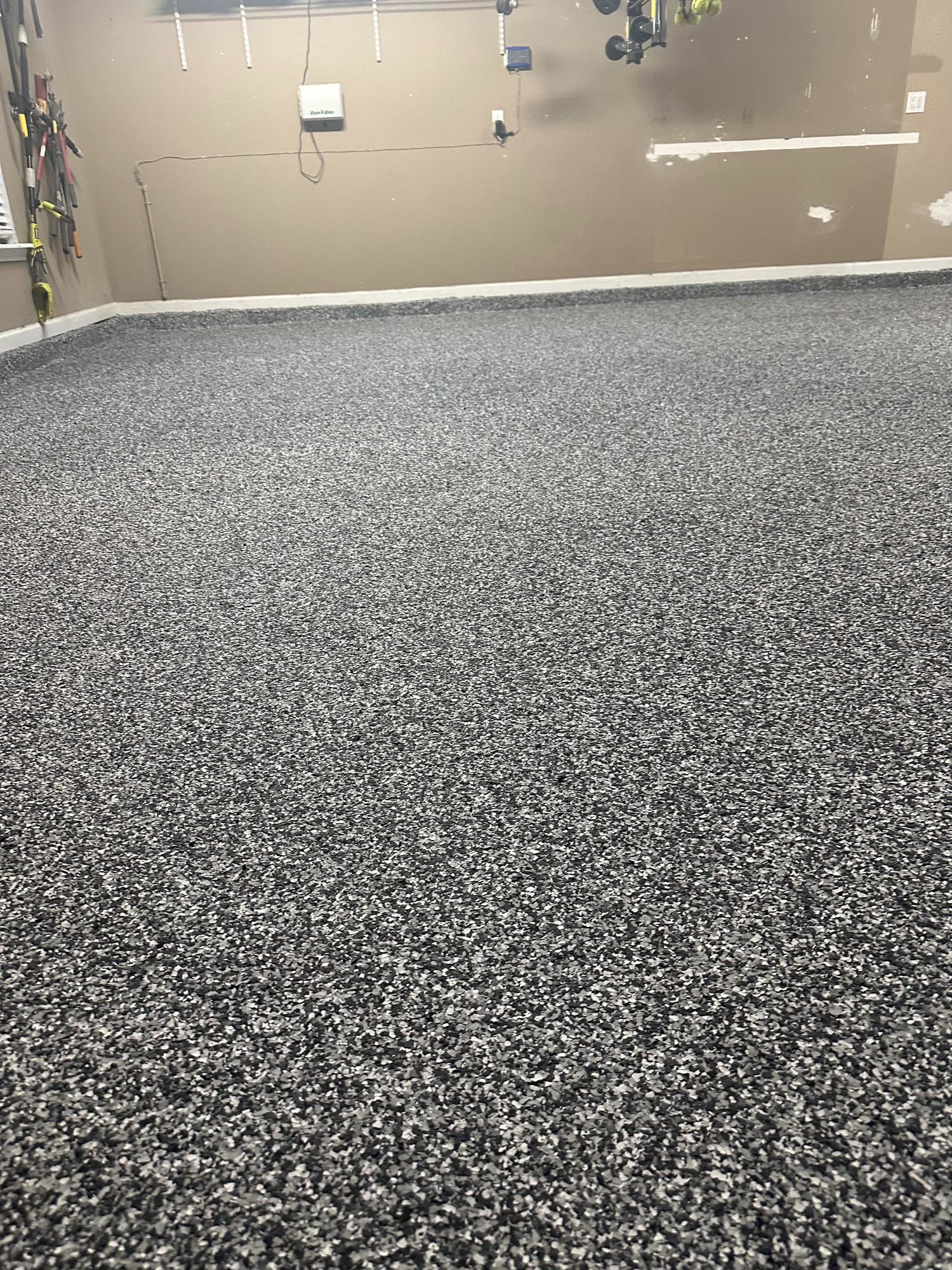 Grey speckled epoxy floor. Light tan walls in a garage.