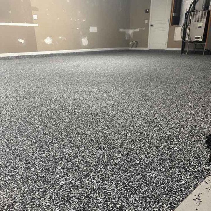 Garage with a speckled, gray epoxy floor. Beige walls and a white door are visible.