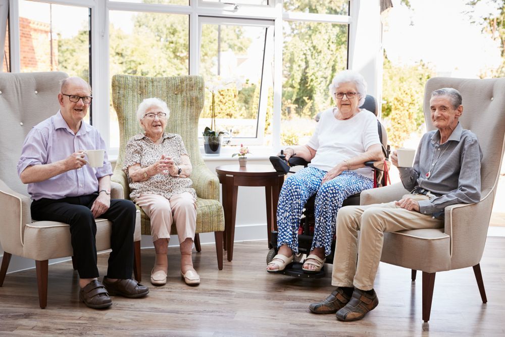 Portrait Of Excited Senior Woman Sitting In Chair In Lounge 
