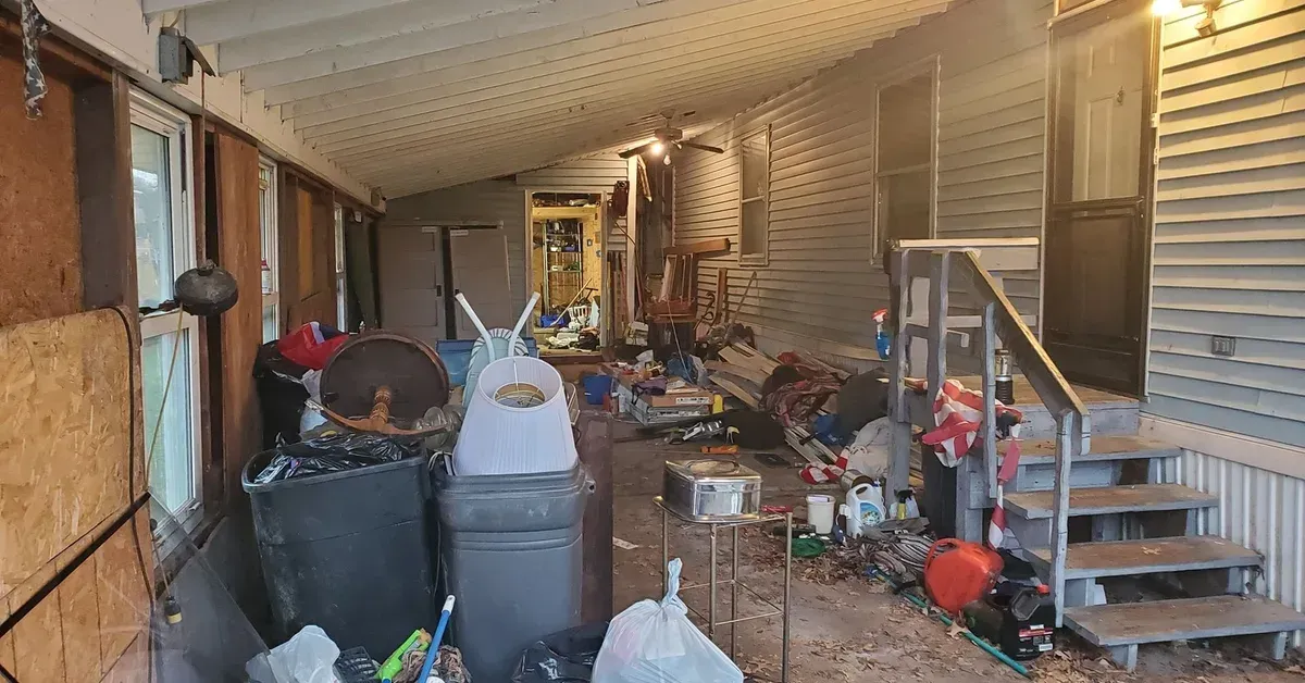 Cluttered covered porch filled with junk bags and debris ready for removal in Northeast Ohio