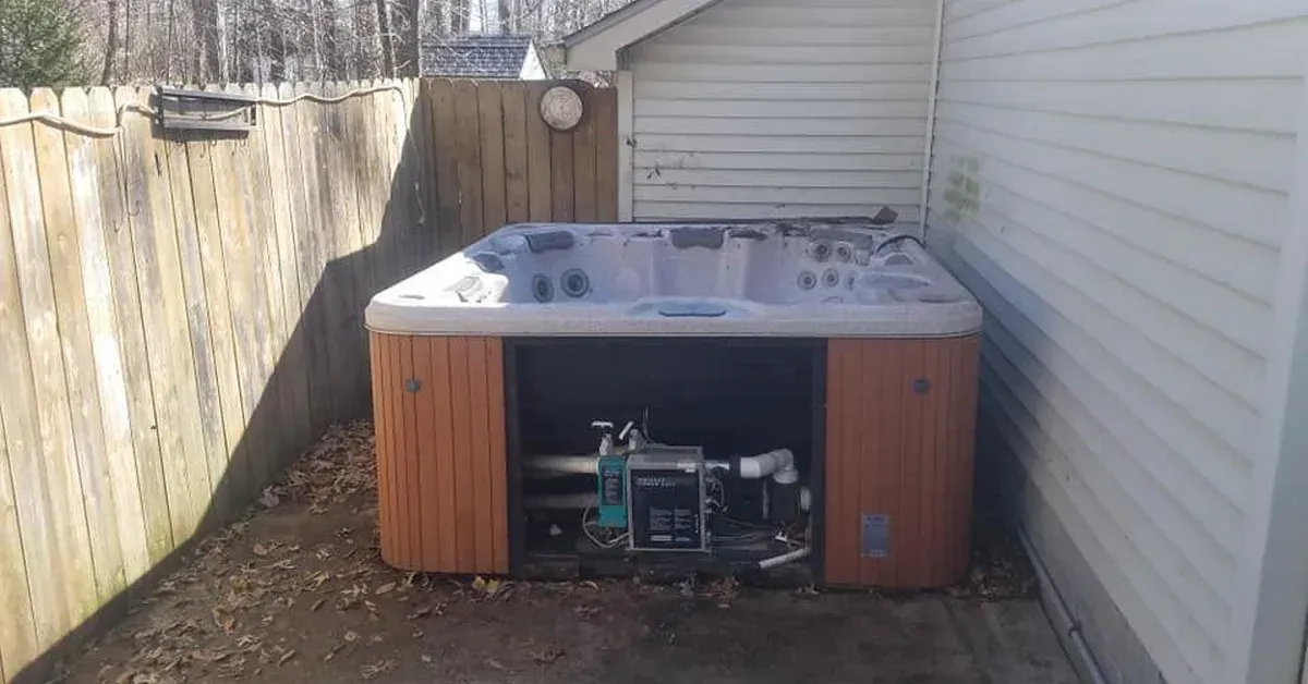 Old hot tub against fence and house siding ready for removal in Northeast Ohio