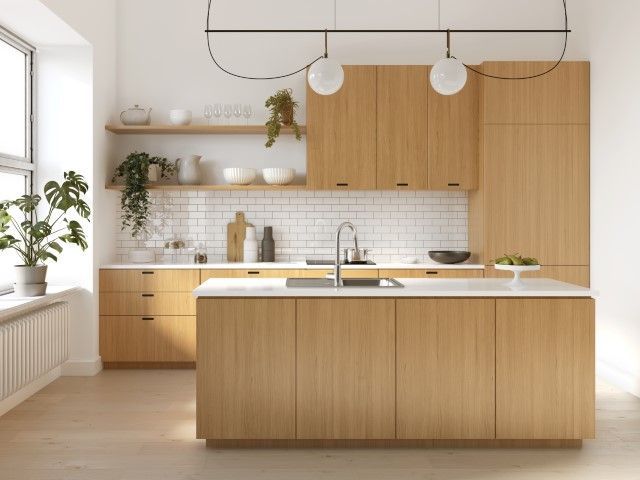 Modern kitchen with light wood cabinets, white countertops, and open shelving, featuring plants and globe pendant lights.