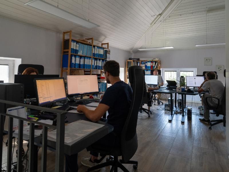 Un uomo è seduto alla scrivania di un ufficio e lavora al computer.