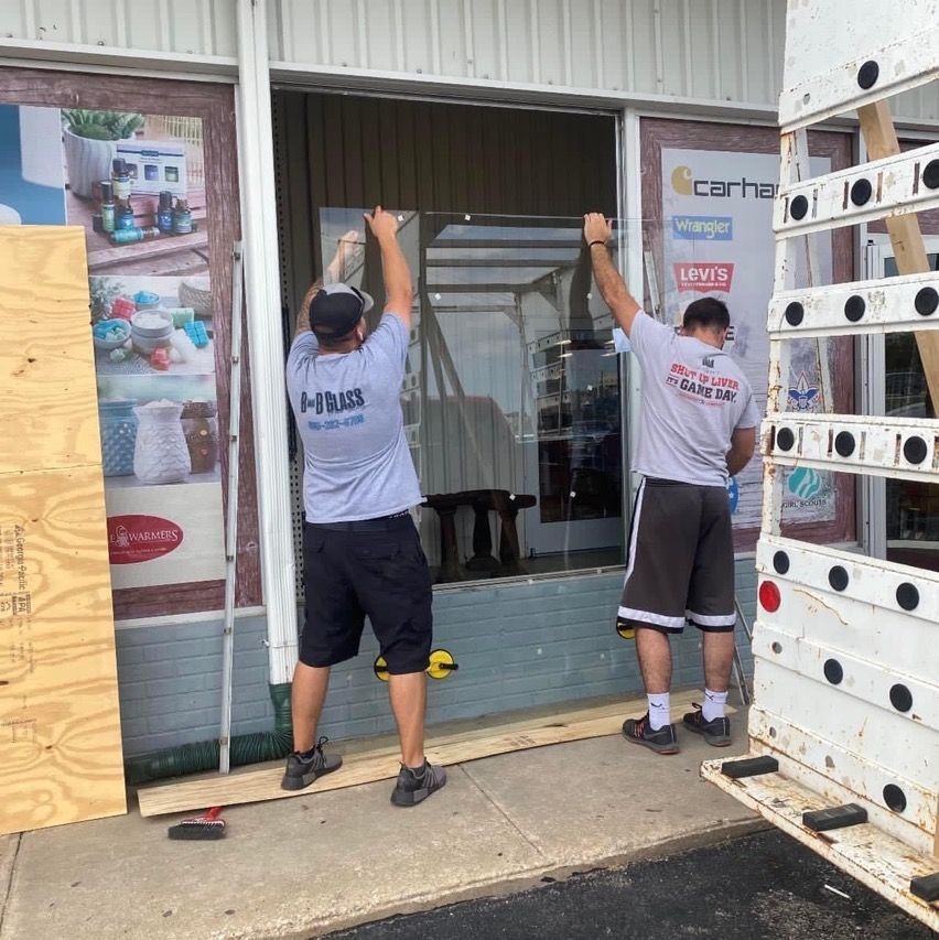 A man wearing a hms shirt is working on a window