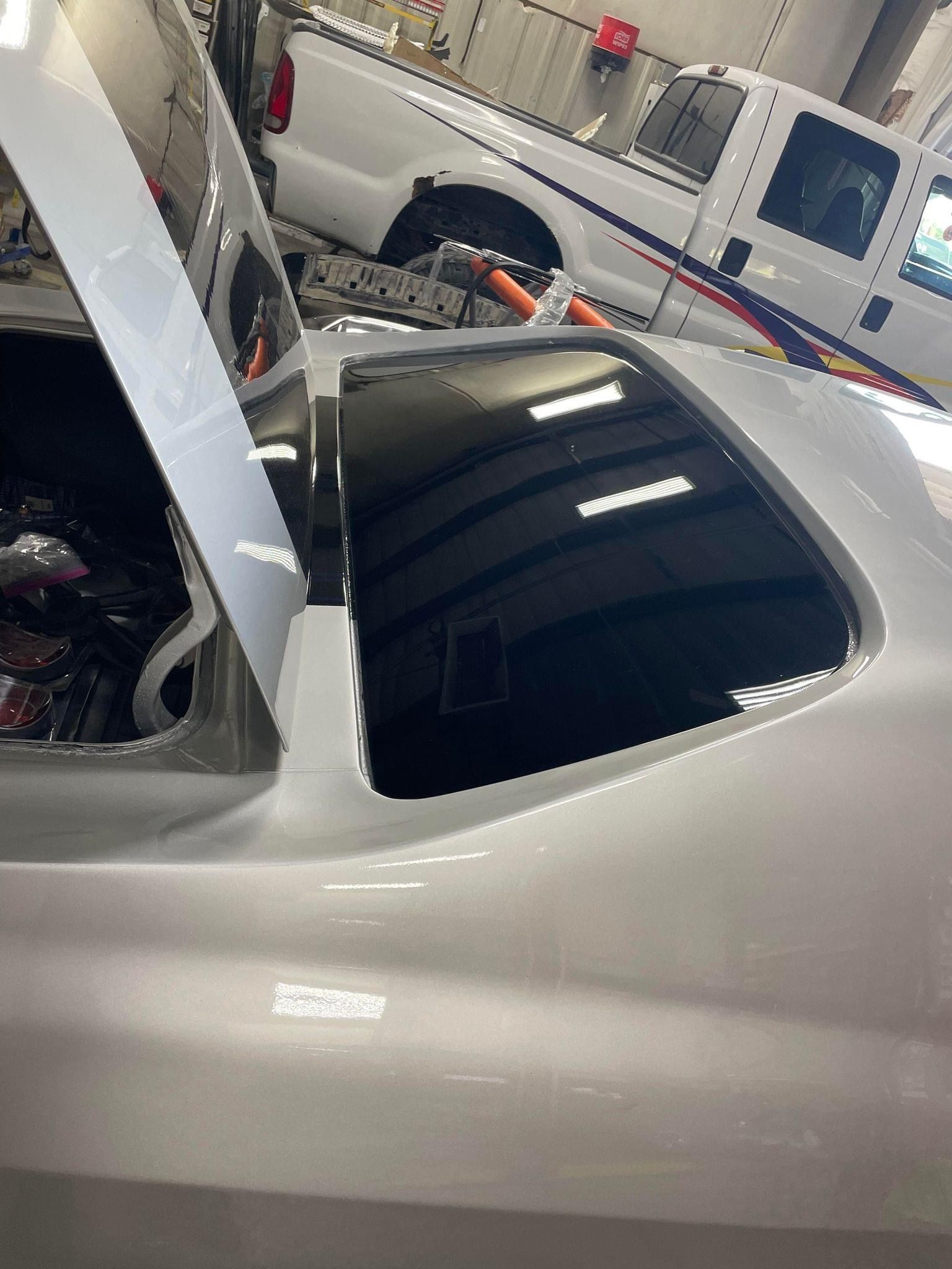 A car is being built in a garage with the sunroof open.