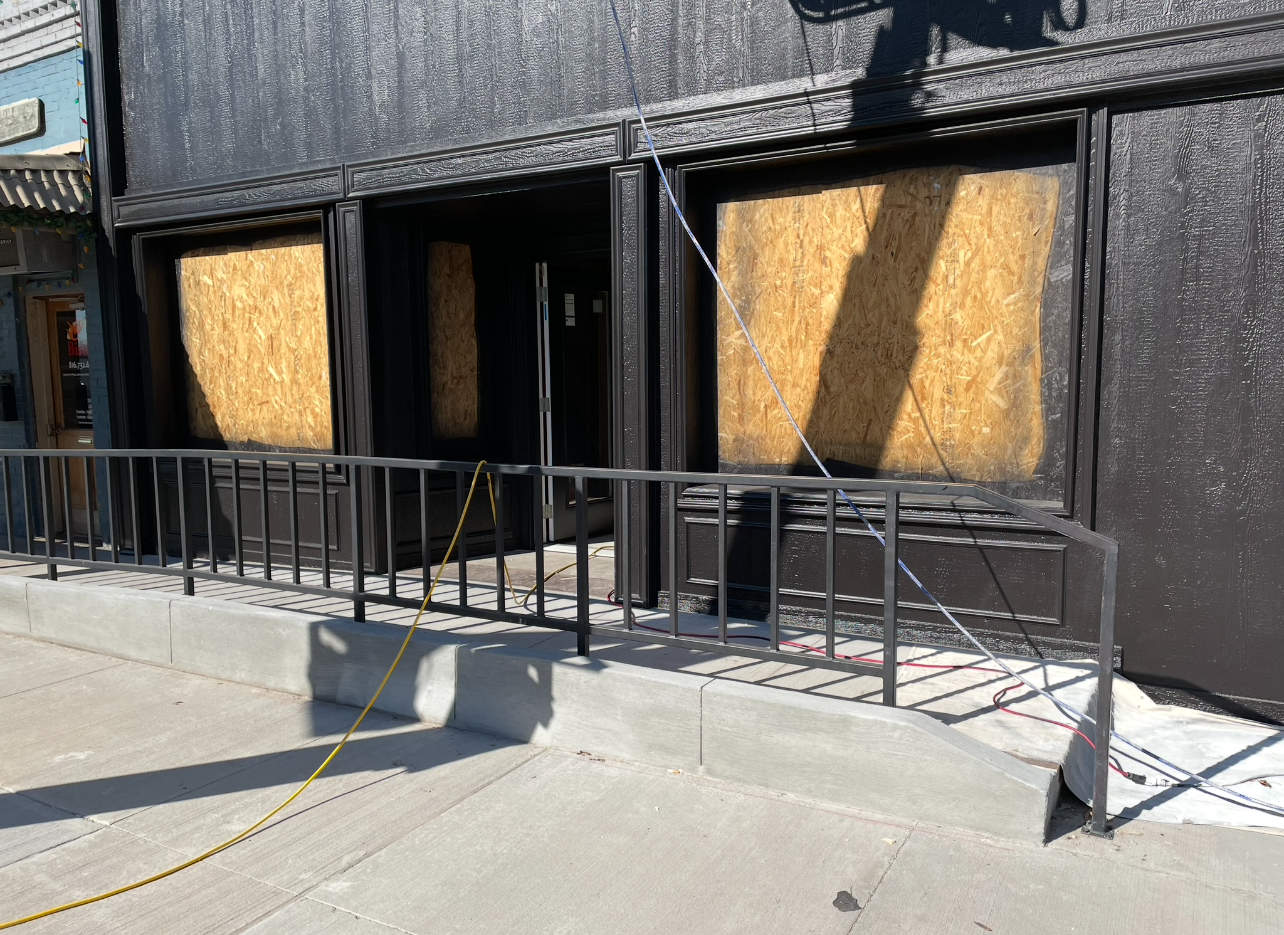 A black building with boarded up windows and a metal railing.