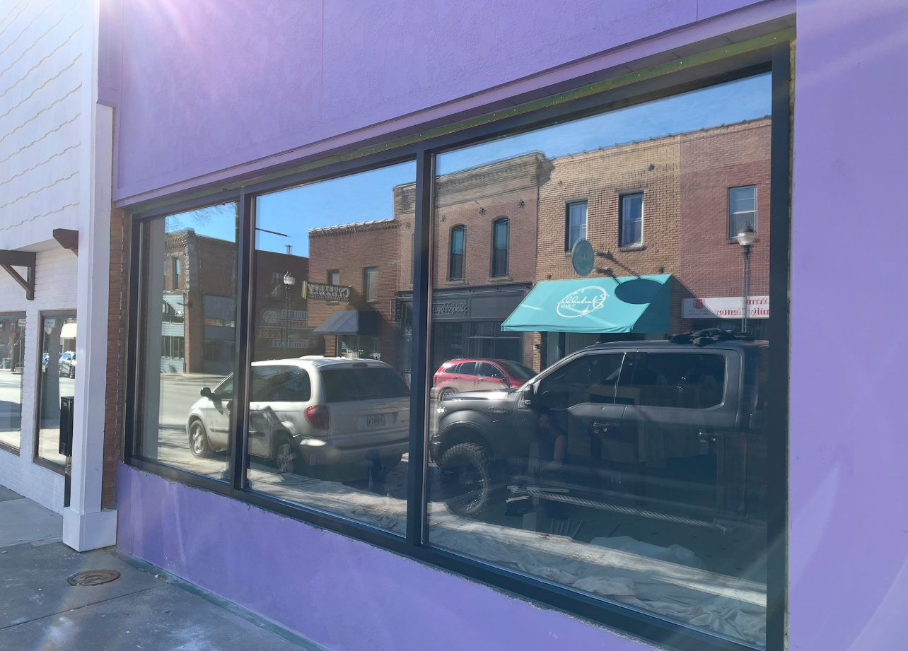 A purple building with a reflection of cars in the windows