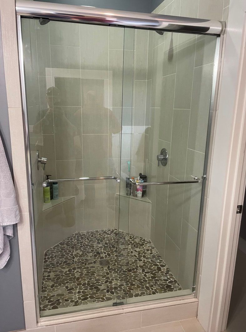 A bathroom with a sliding glass shower door and a tiled floor.