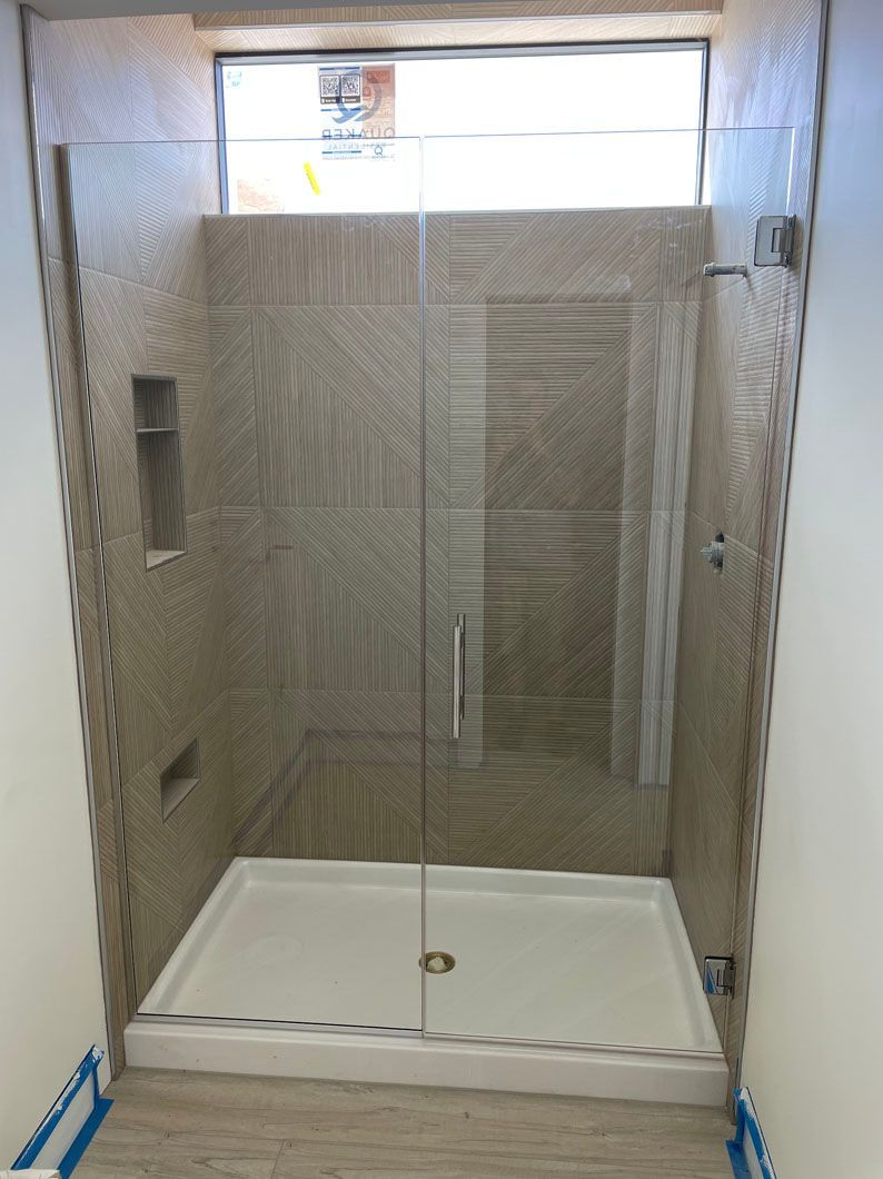 A bathroom with a walk in shower and a window.