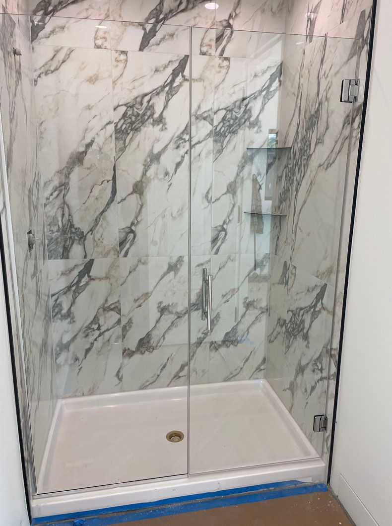 A shower stall with a marble wall and a glass door.