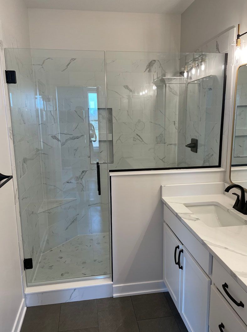 A bathroom with a walk in shower , sink and mirror.