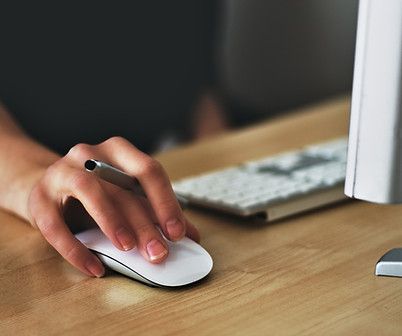 A person is using a computer mouse with a pen in their hand.