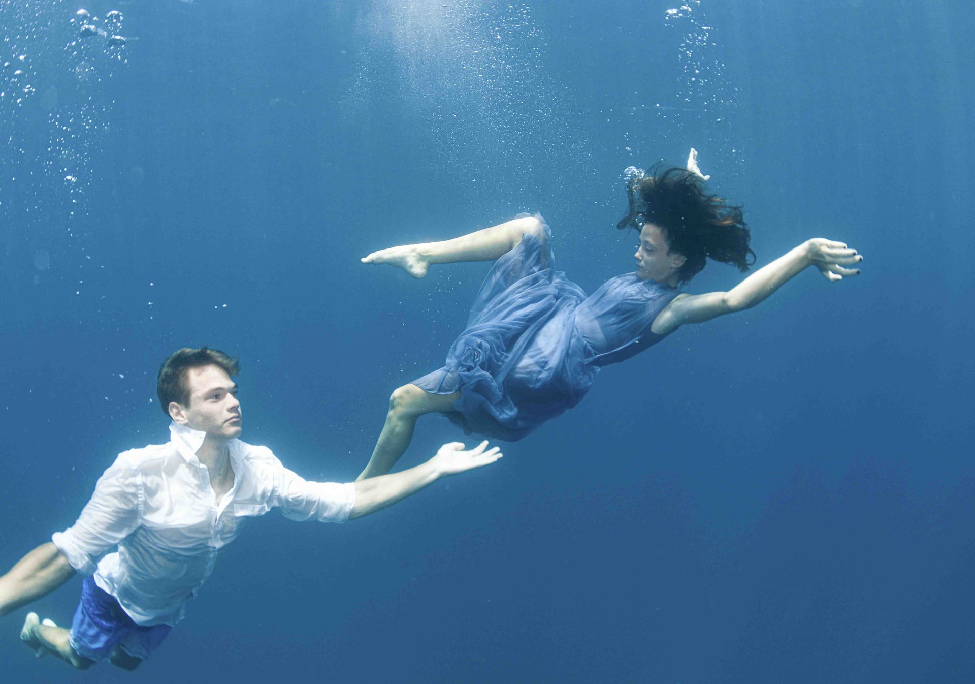 A young girl and boy, who have recently got engaged, performing ballet style moves in the Fiji ocean