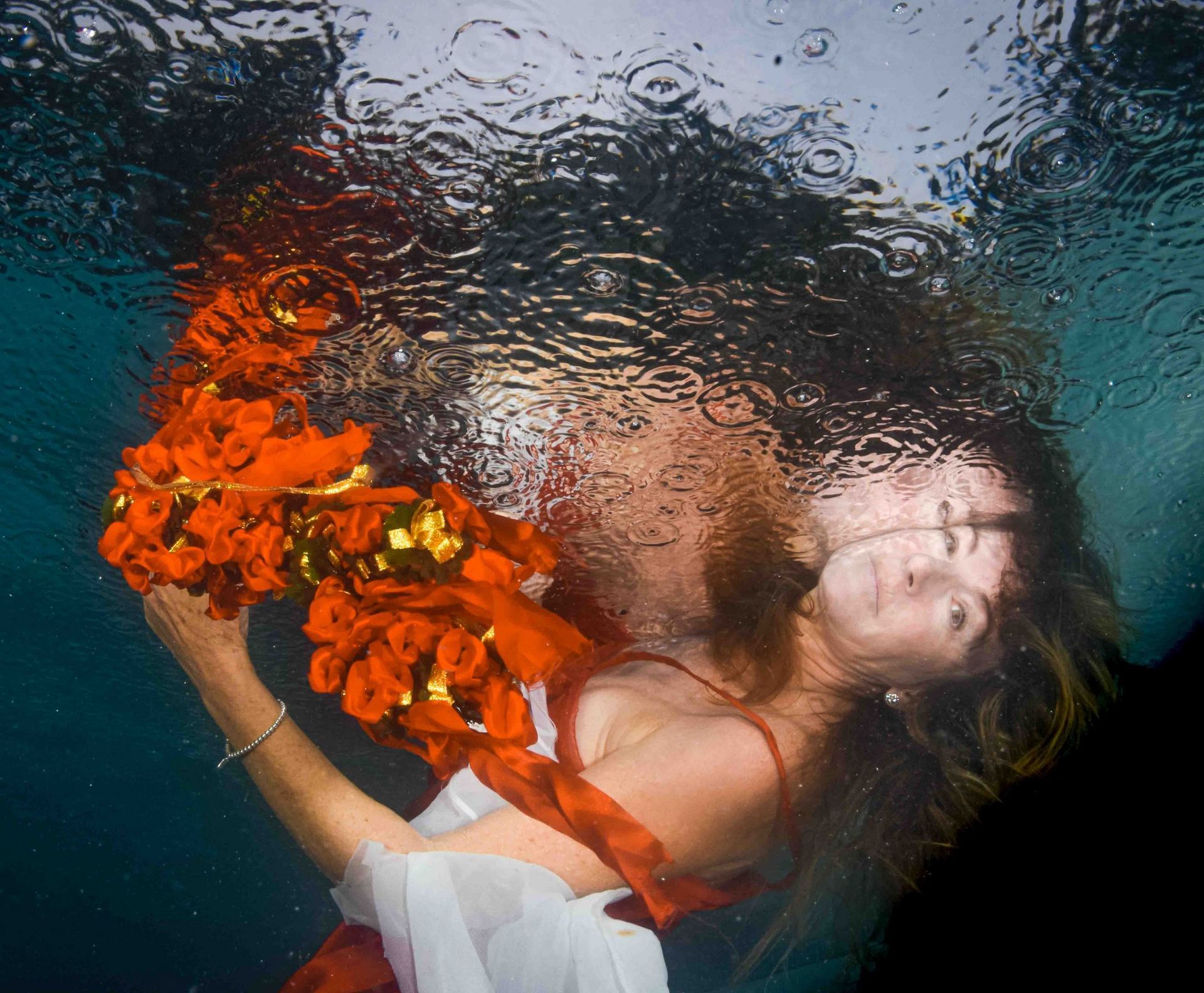 A fine art portrait of a a Fiji bride lying under the surface of the water creating a reflection