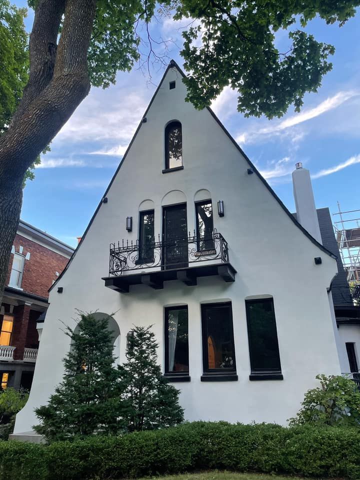 une maison blanche avec un balcon et un arbre devant