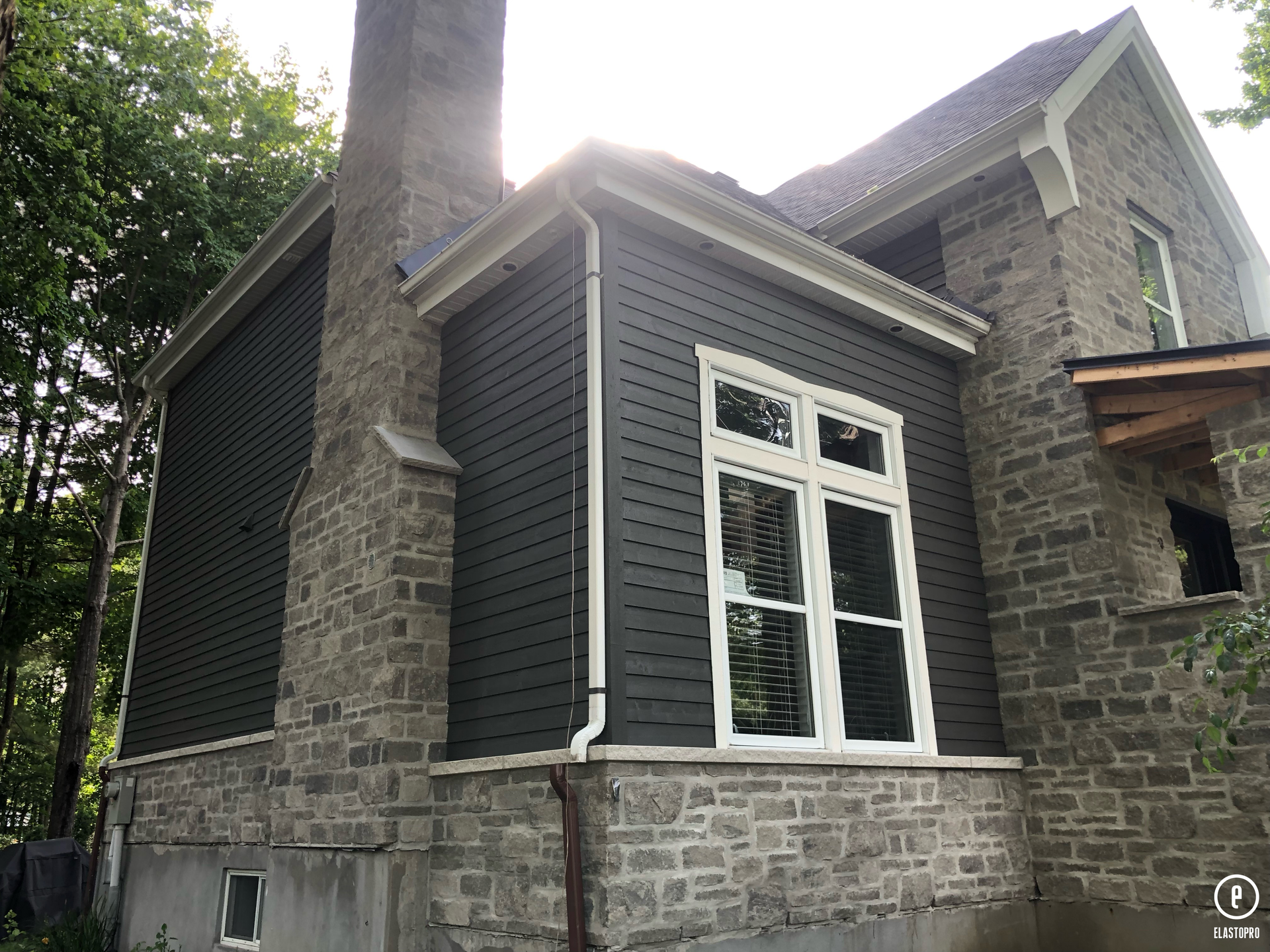 une grande maison en brique avec une grande fenêtre et une cheminée.