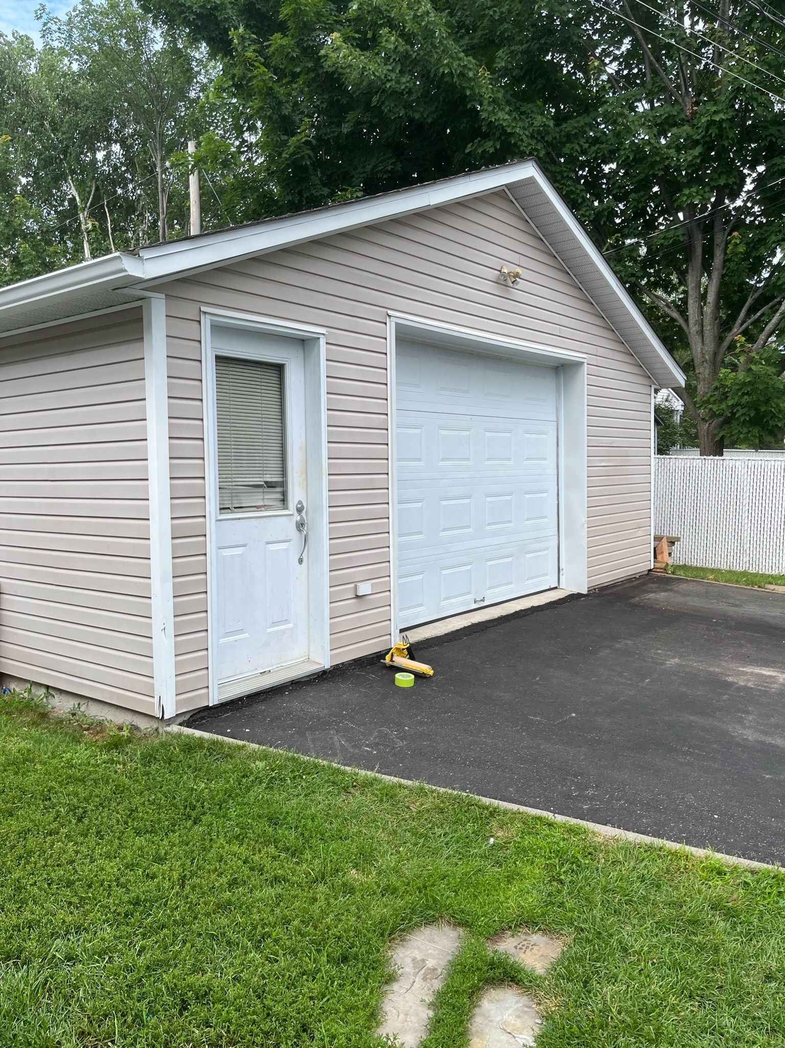 un garage avec une porte de garage blanche se trouve dans la cour d'une maison.