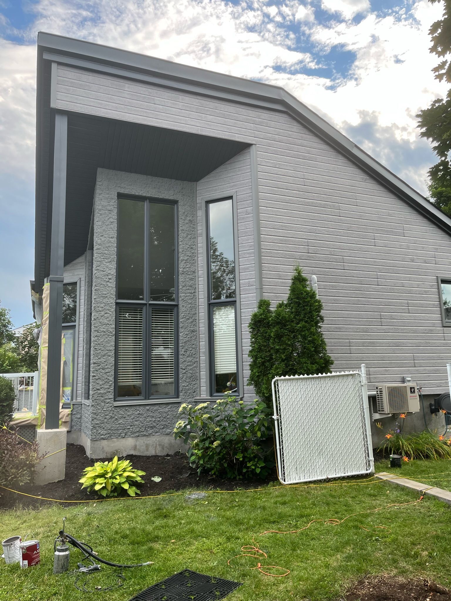 une grande maison blanche avec de nombreuses fenêtres se trouve au sommet d'une pelouse verte et luxuriante.