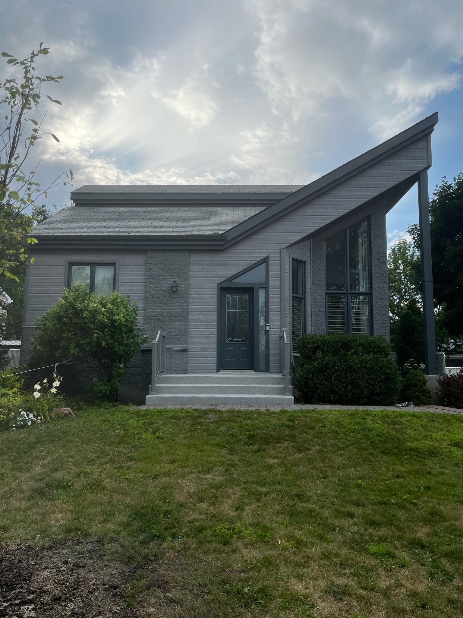 une petite maison avec une grande pelouse devant