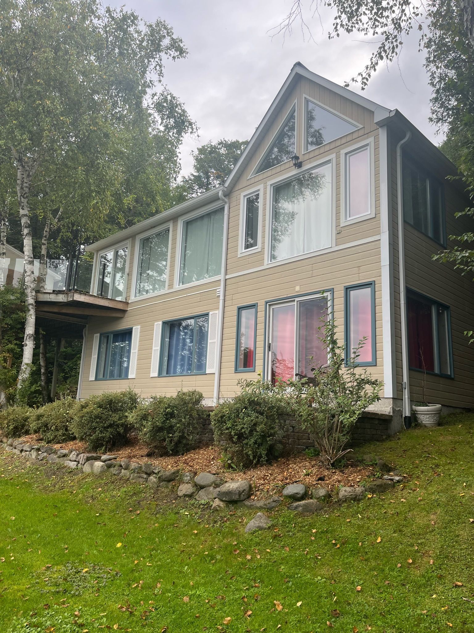 une grande maison avec de nombreuses fenêtres se trouve au sommet d'une colline verdoyante.