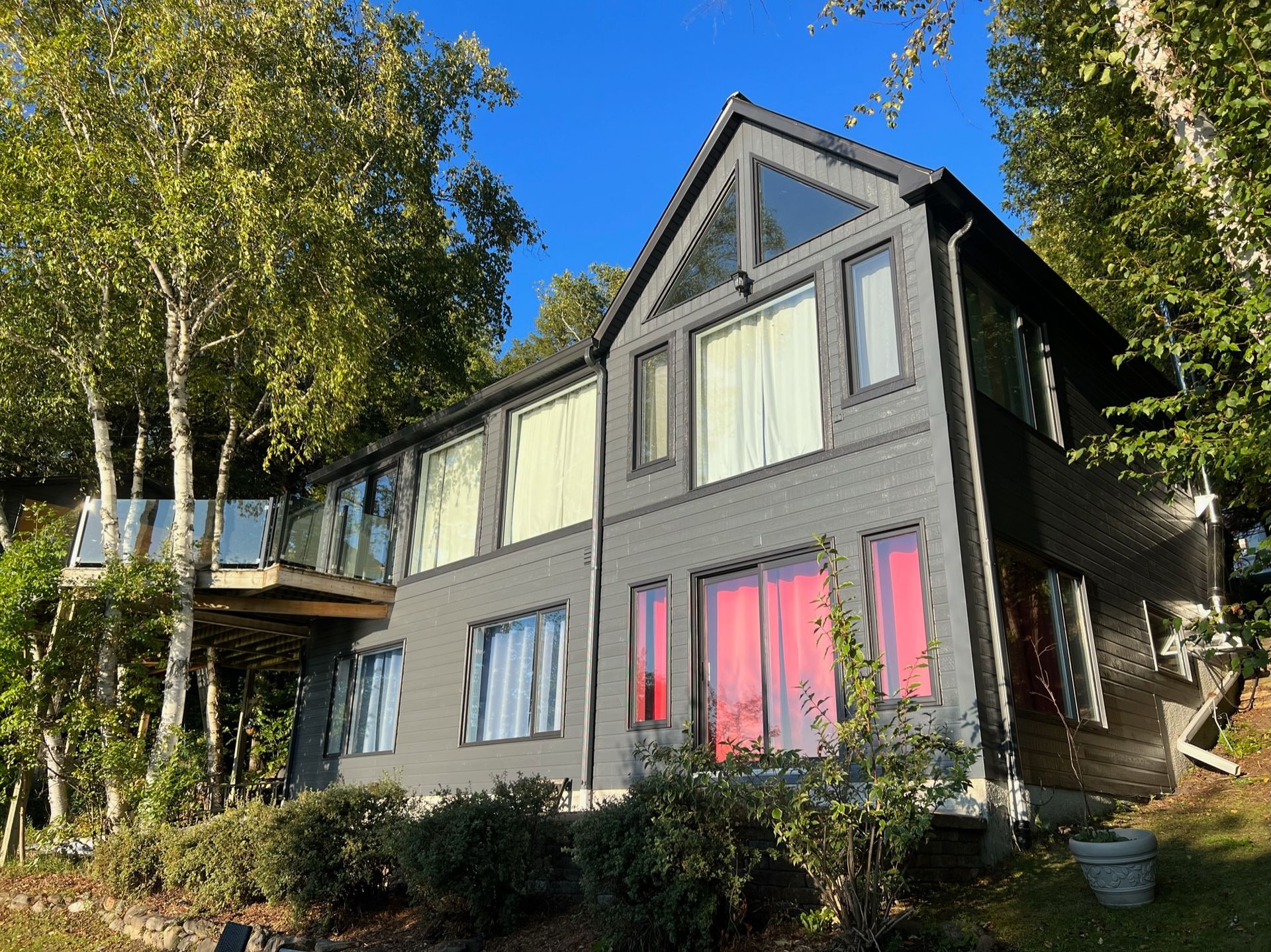 une grande maison avec beaucoup de fenêtres est entourée d'arbres.