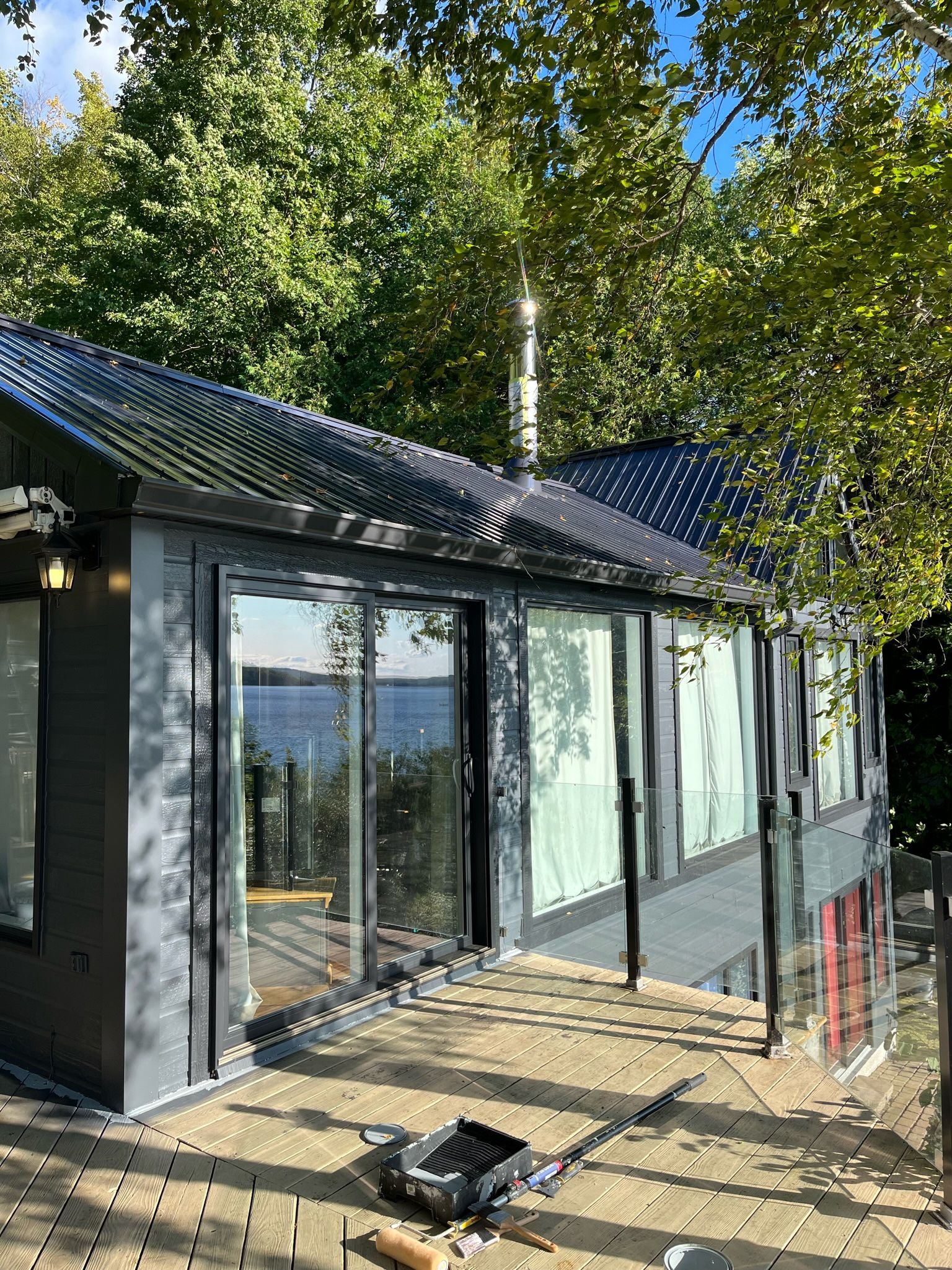 une maison avec beaucoup de fenêtres et un toit est entourée d'arbres.