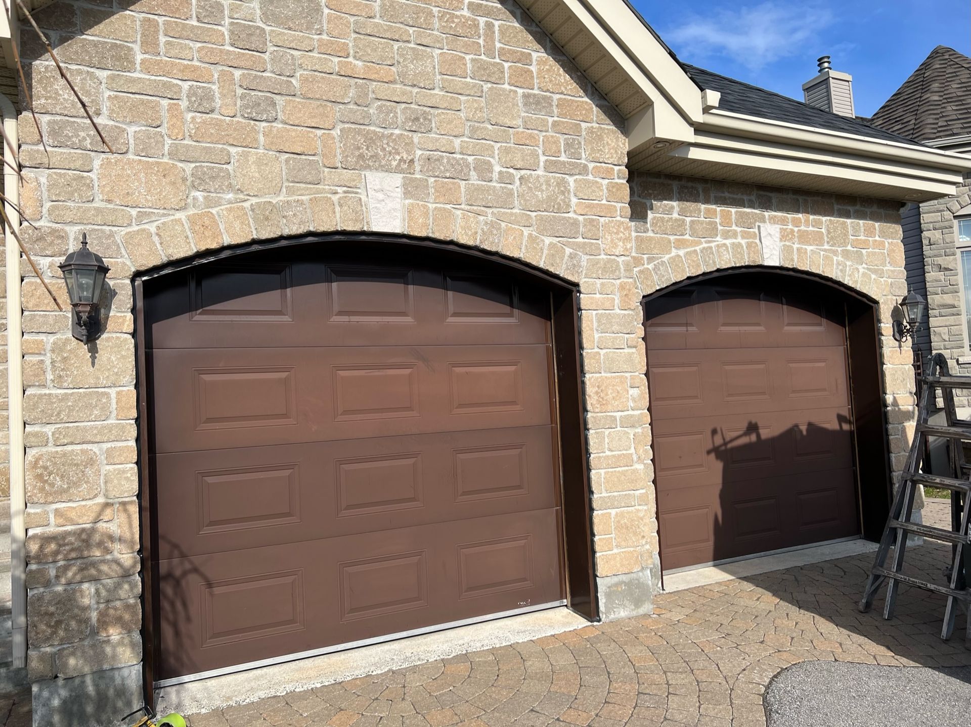 quelques portes de garage marron sur un bâtiment en brique.