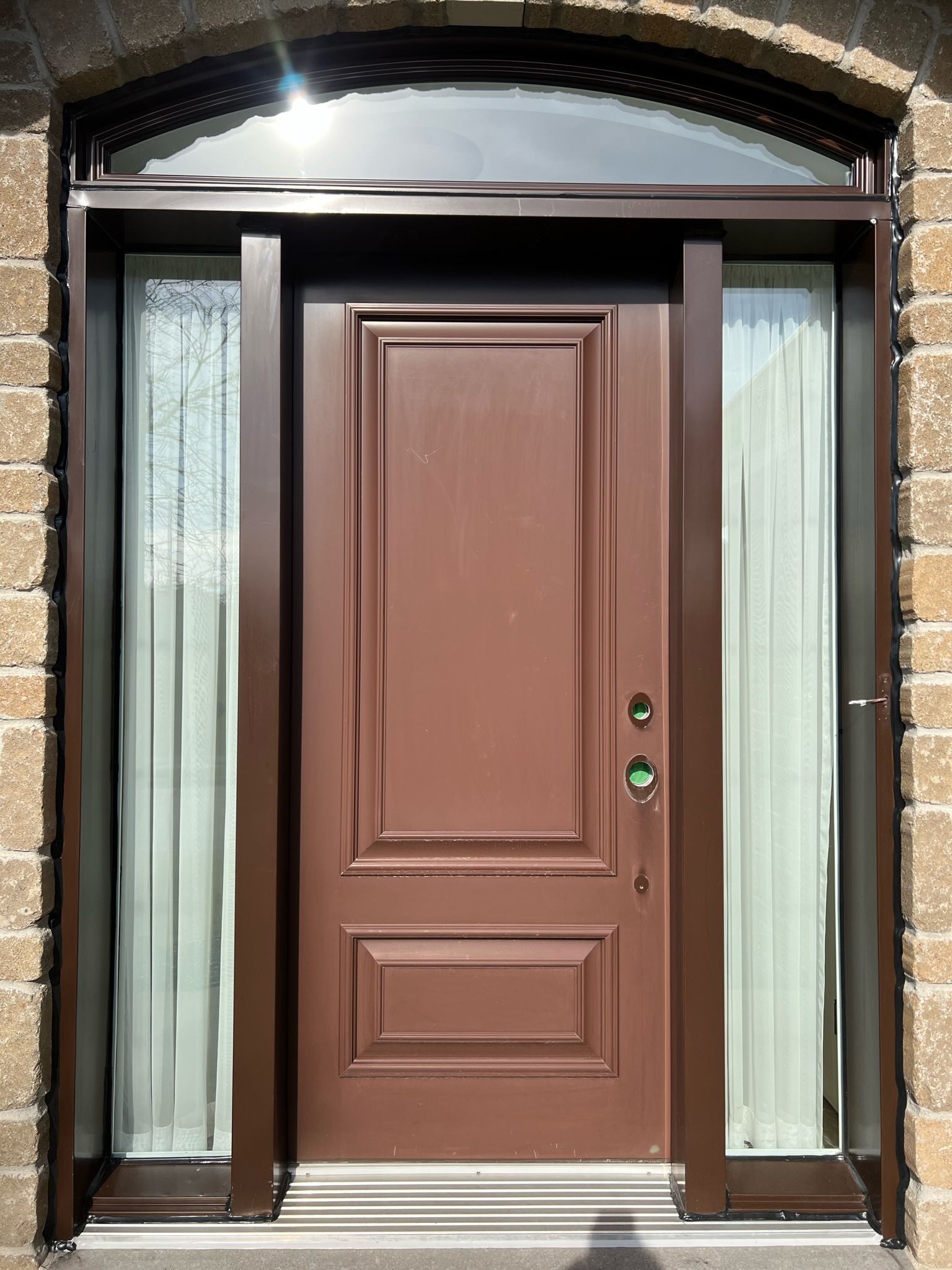 une porte marron avec un mur de briques derrière