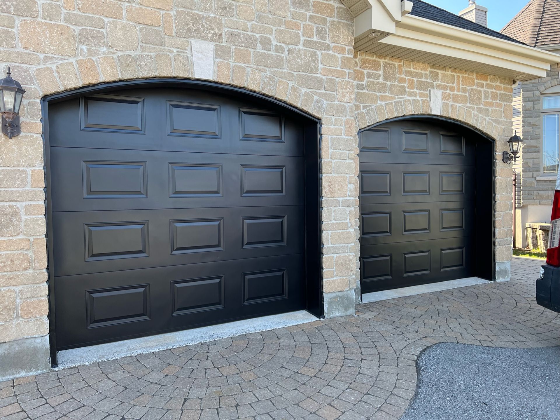 quelques portes de garage noires sur un bâtiment en brique.
