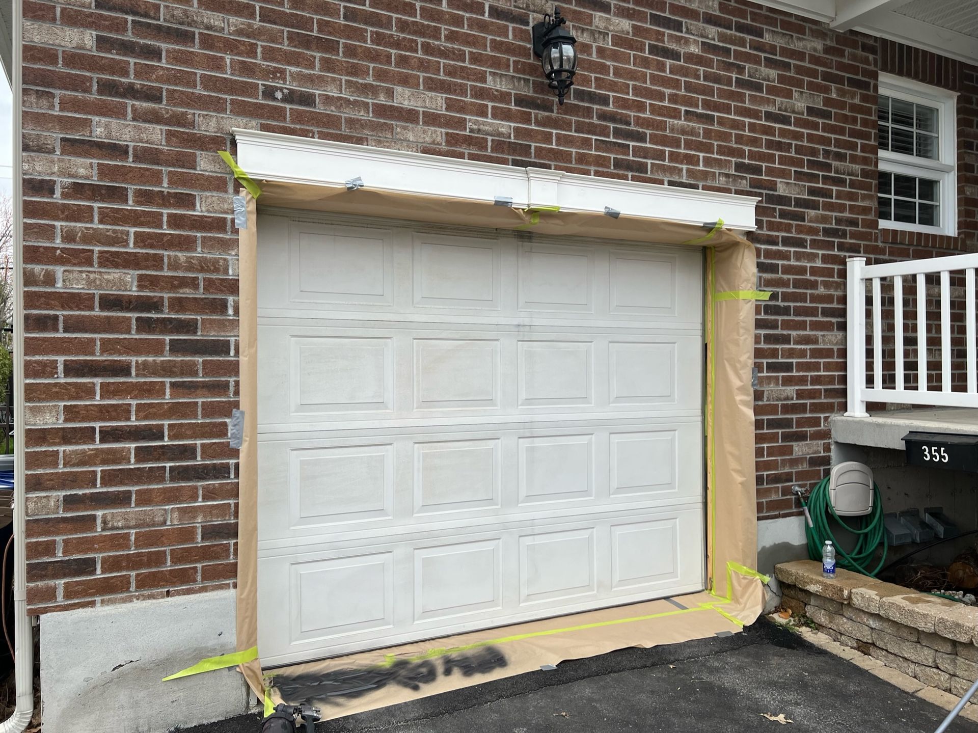 une porte de garage blanche se trouve devant une maison en brique.