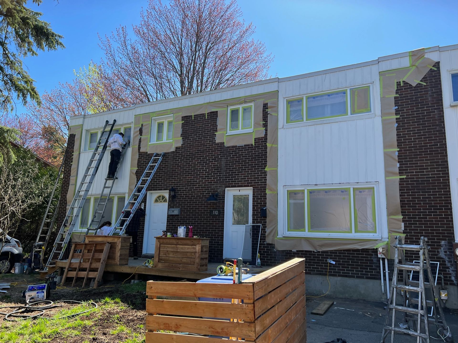 un homme fait des travaux sur le côté d'une maison avec une échelle.