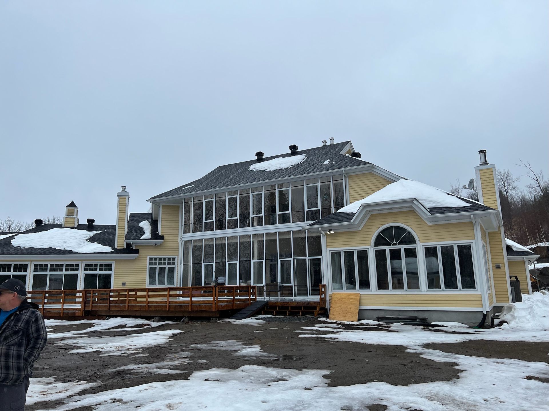 un homme se tient devant une grande maison dans la neige.