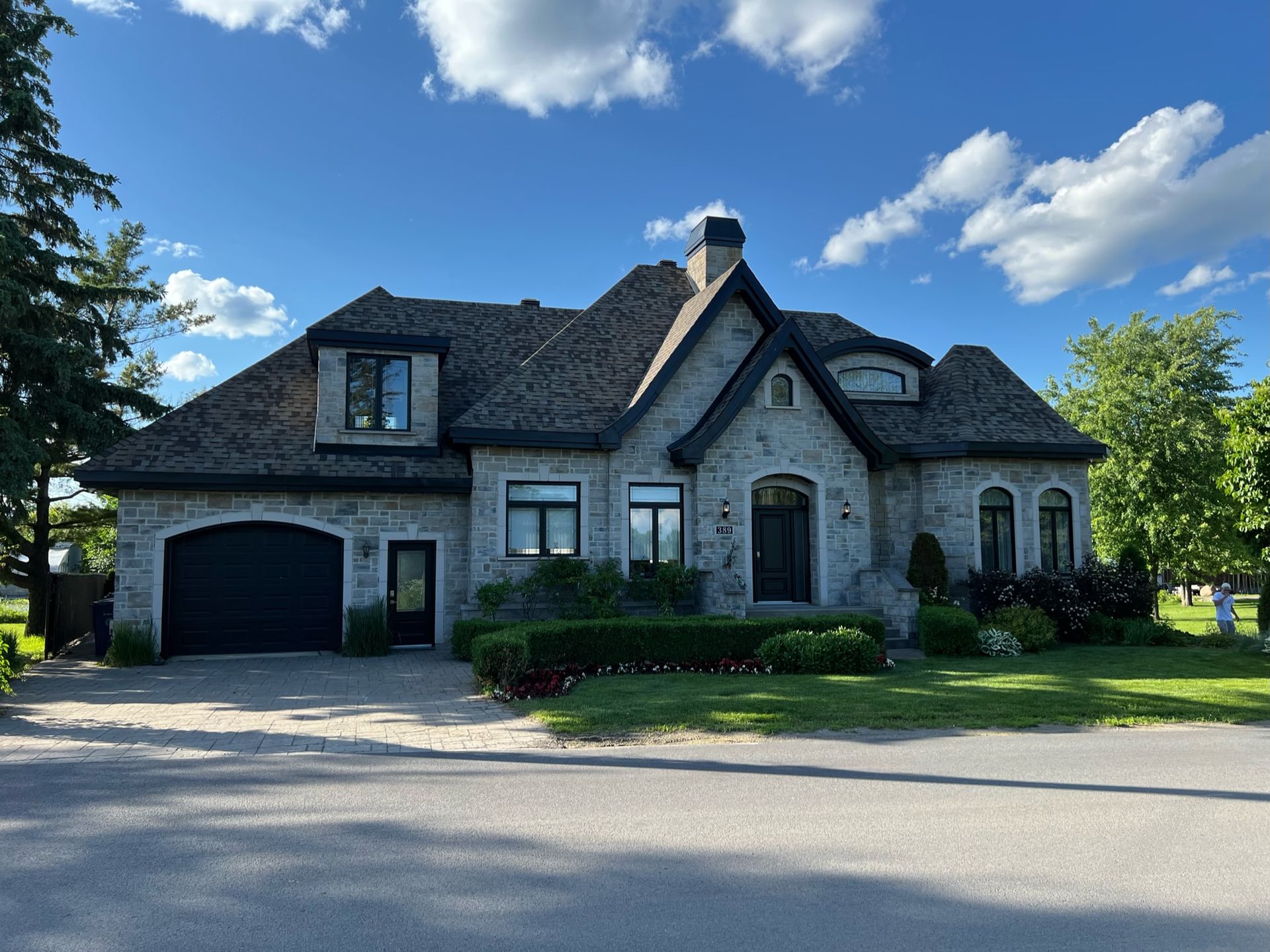 une grande maison avec un garage noir et un ciel bleu en arrière-plan