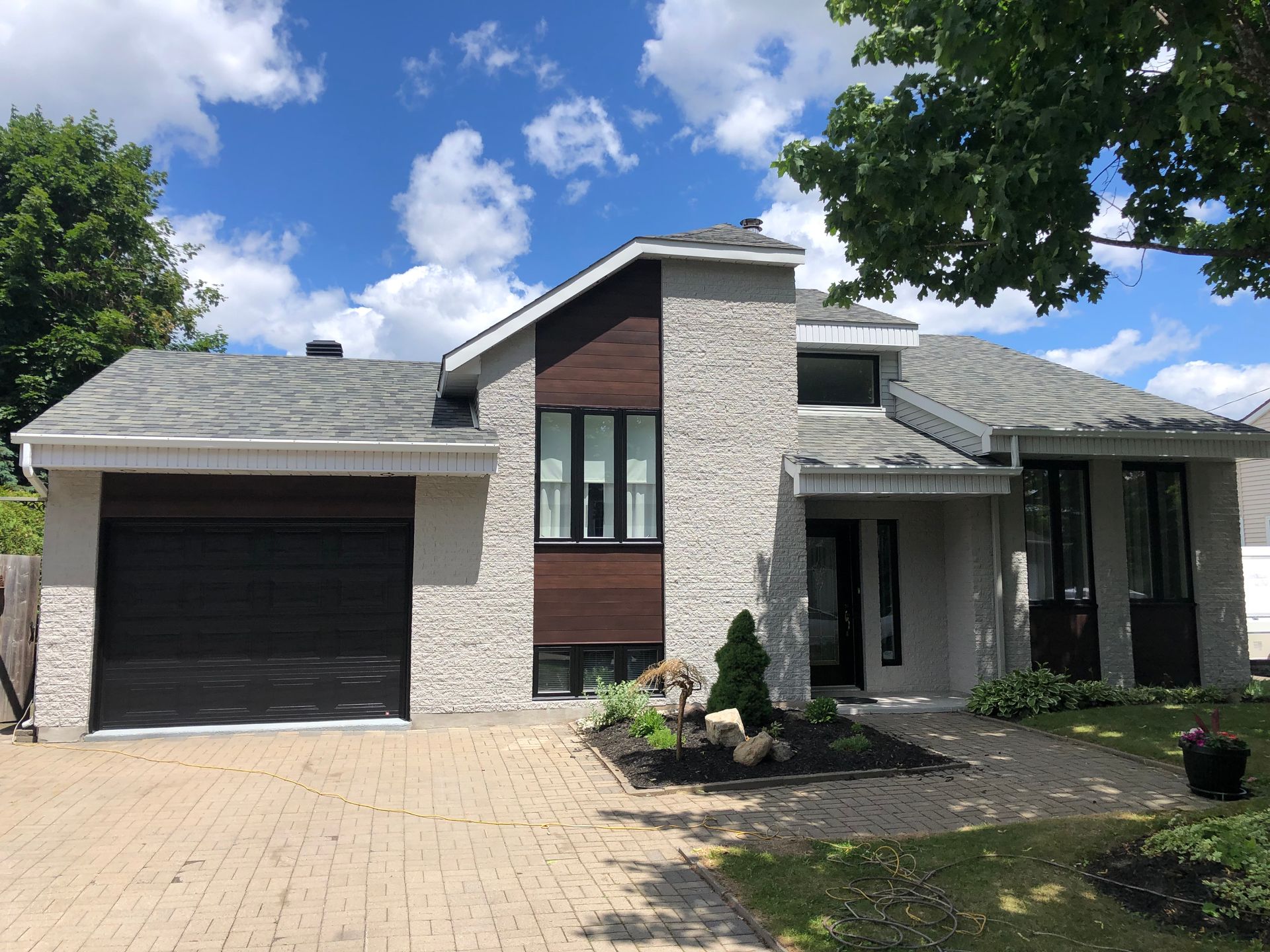 une grande maison avec un toit gris et une porte de garage noire