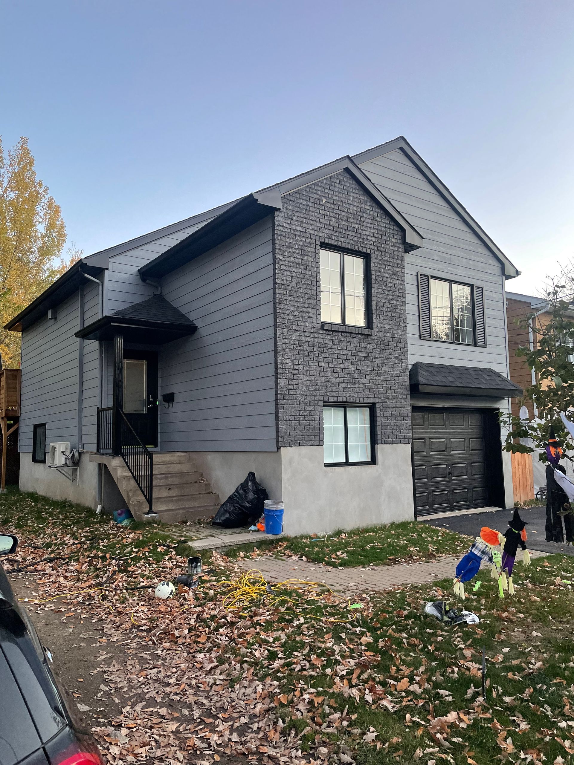 A gray house with a car parked in front of it.