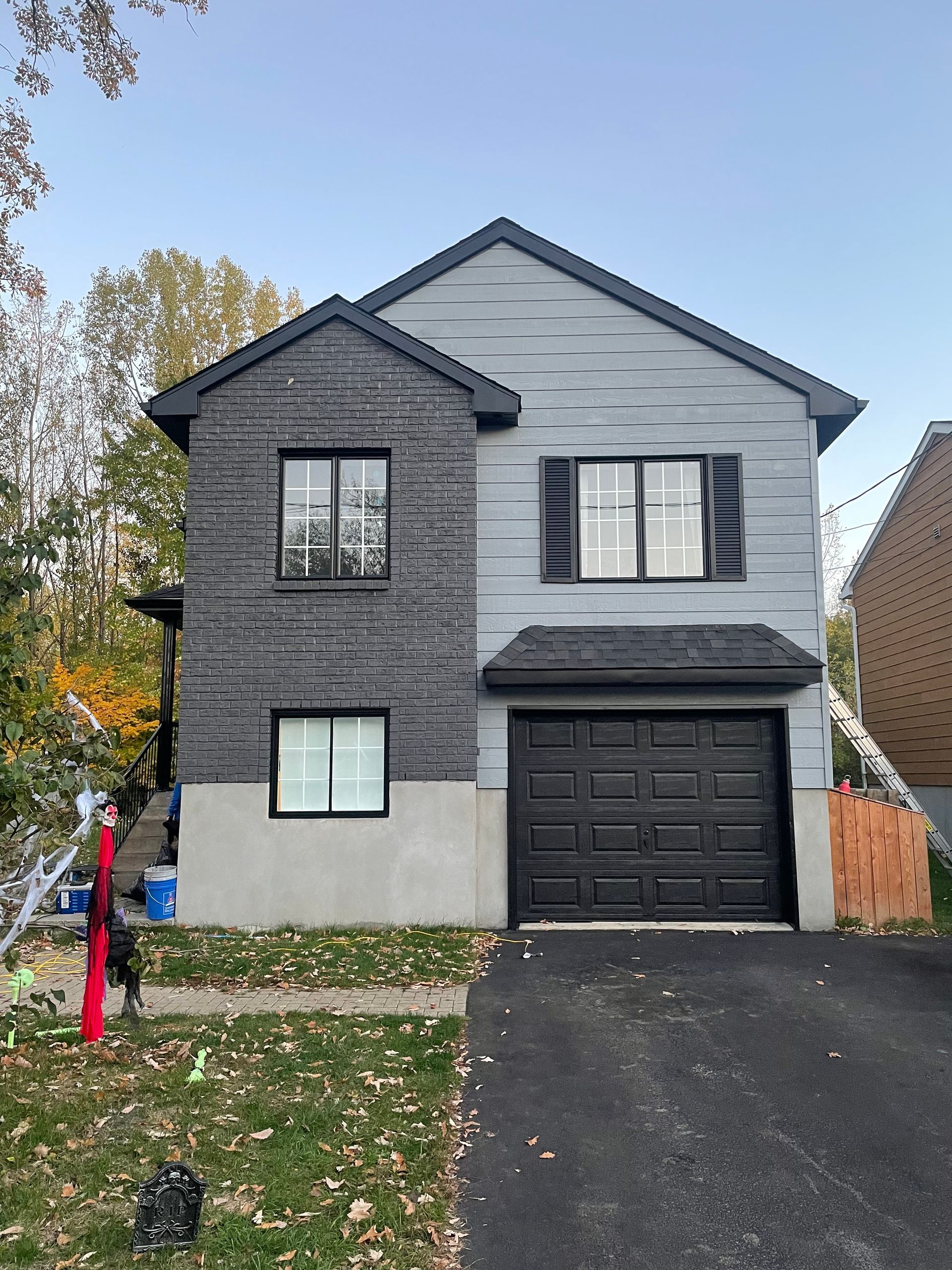 la façade d'une maison avec une porte de garage noire