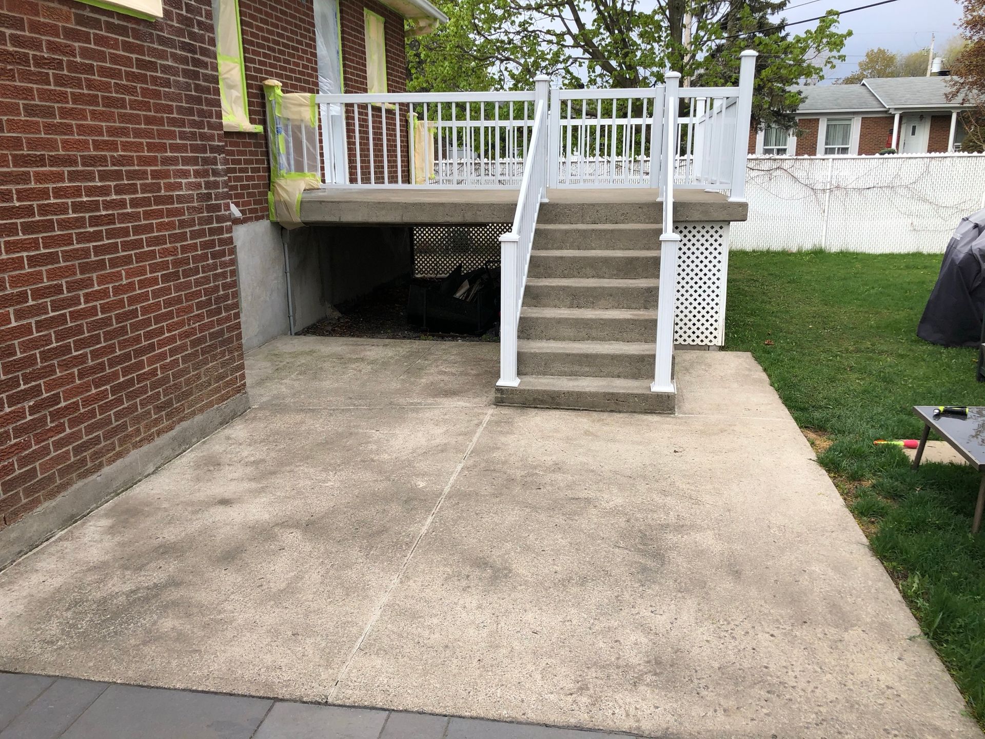 une maison en brique avec un patio en béton et des escaliers menant à une terrasse.