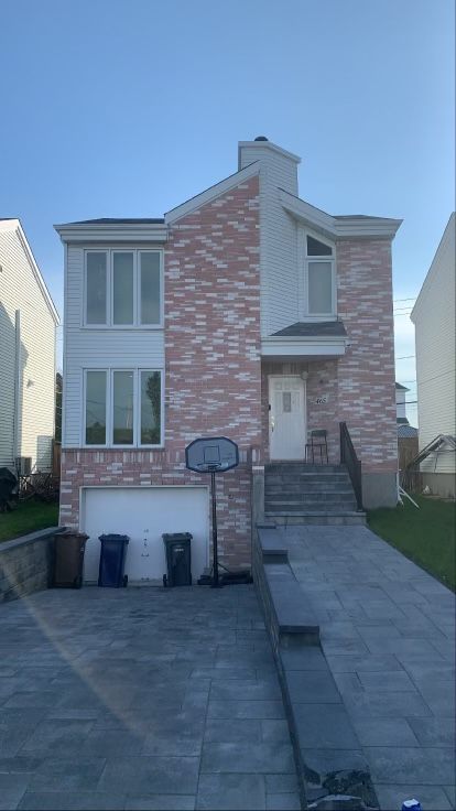 une grande maison en brique avec un panier de basket devant.