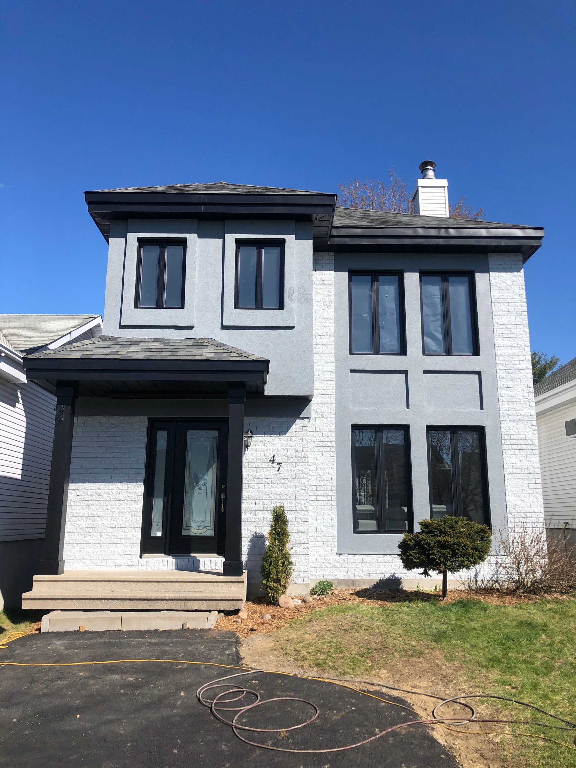 une maison blanche avec des fenêtres noires et une cheminée sur le toit.