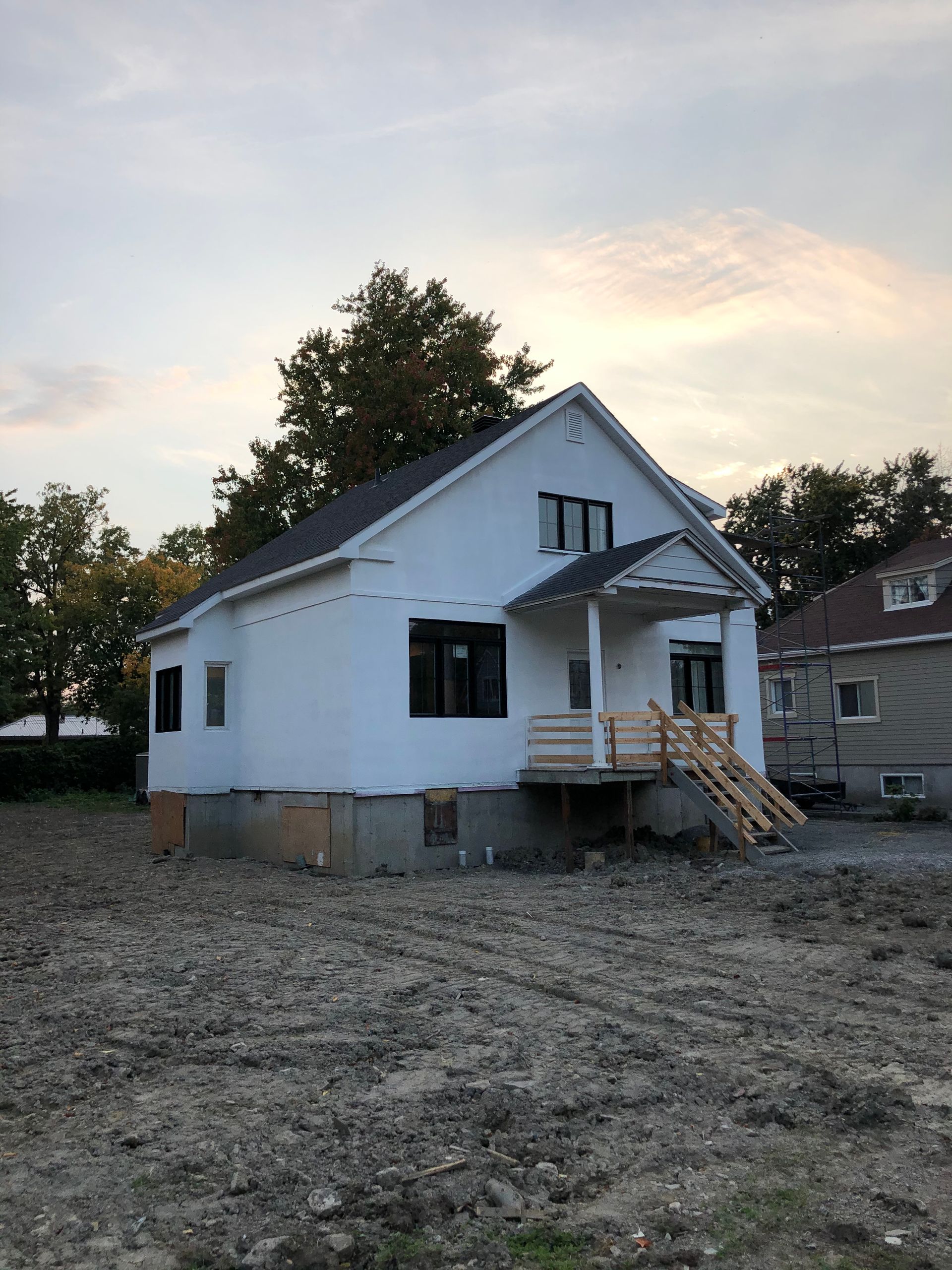 une maison blanche est assise au milieu d'un champ de terre.